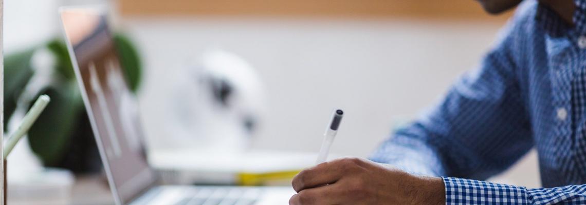 Man writing near laptop